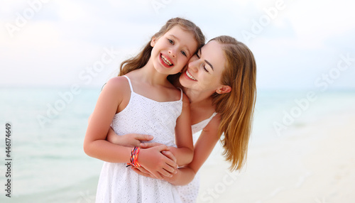 Happy mother and daughter hugging on beach