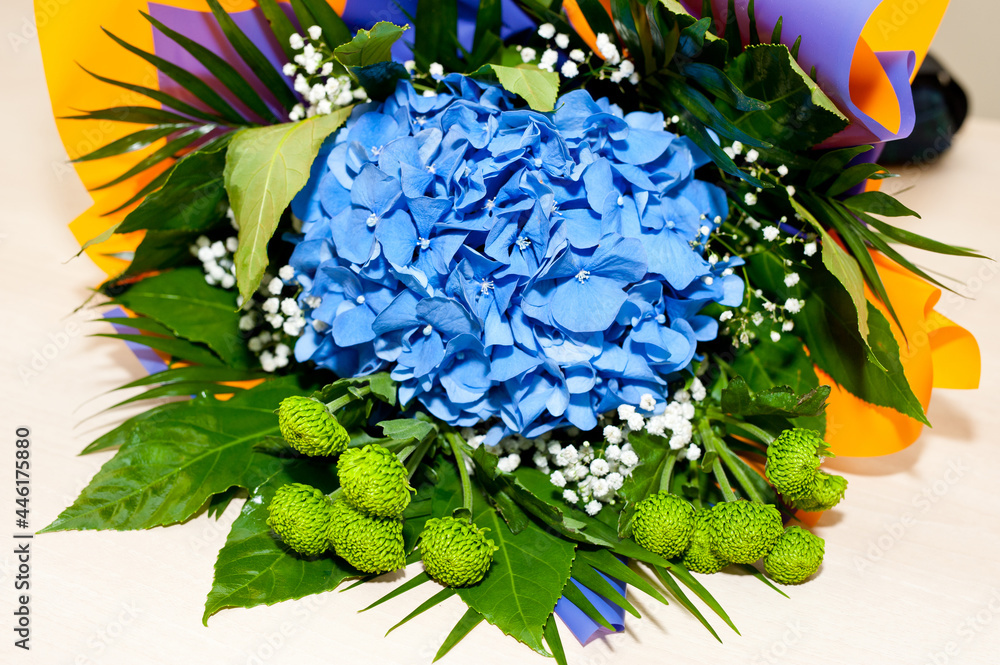 Bouquet with blue, white and other flowers, decorated with colored paper.