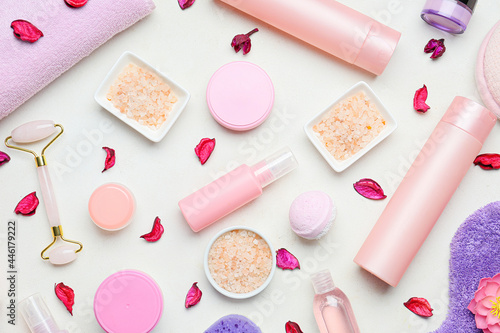 Different bath supplies and flower petals on light background