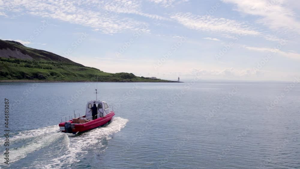A Small Cargo Ferry at Sea Motoring Alongside an Island A Small Cargo Ferry at Sea Motoring Alongside an Island