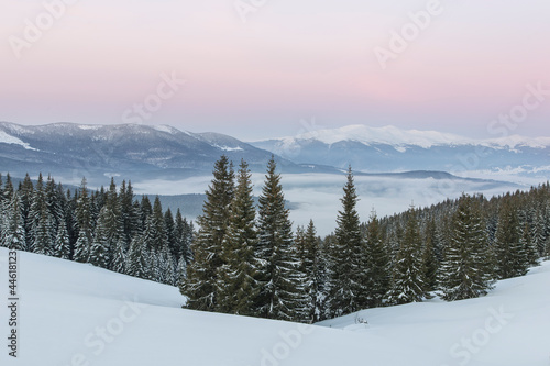 Sunset in the winter Carpathian mountains. Sun disk and long rays at sunset in the winter mountains. Picturesque sunset in the mountains.Vibrant photo wallpaper.