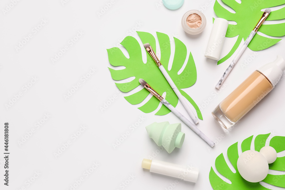 Makeup supplies with tropical leaves on white background Makeup supplies with tropical leaves on white background