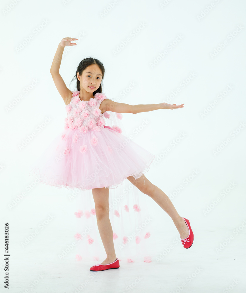 Isolated full body studio shot of little cute pretty Asian ballerina kid wears pink beautiful roses flowers ballet dress and red shoes smiling posing dancing happily in front of white background Isolated full body studio shot of little cute pretty Asian ballerina kid wears pink beautiful roses flowers ballet dress and red shoes smiling posing dancing happily in front of white background