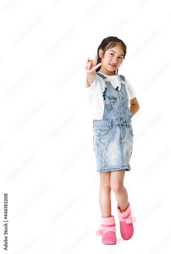Portrait close up isolated studio shot of young pretty cute girl in jeans denim skirt overalls standing look at camera hold hands up overhead show two fingers peace sign in front of white background Portrait close up isolated studio shot of young pretty cute girl in jeans denim skirt overalls standing look at camera hold hands up overhead show two fingers peace sign in front of white background