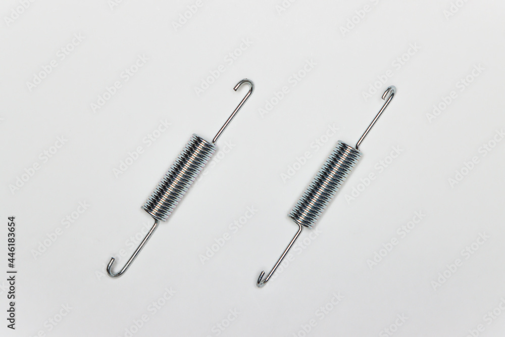 Two long springs for repairing the brakes of the machine. Set of spare parts for car brake repair. Details on white background, copy space available. UHD 4K. Two long springs for repairing the brakes of the machine. Set of spare parts for car brake repair. Details on white background, copy space available. UHD 4K.