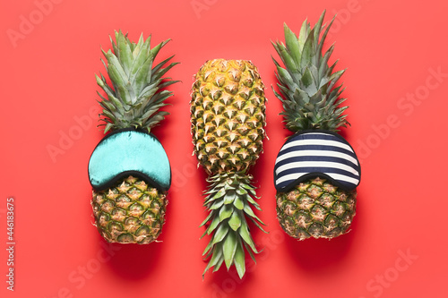 Fresh pineapples in sleeping masks on color background