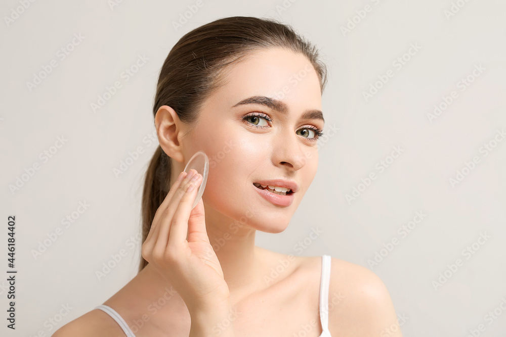 Beautiful young woman with makeup sponge on grey background Beautiful young woman with makeup sponge on grey background