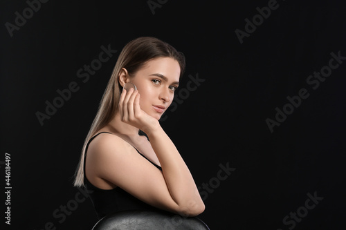 Beautiful young woman with makeup sponge on dark background