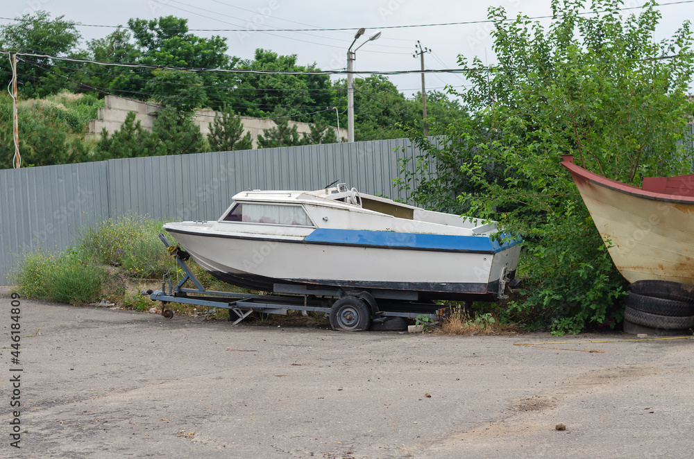 An old dilapidated fishing boat on a trailer in front of a gray An old dilapidated fishing boat on a trailer in front of a gray