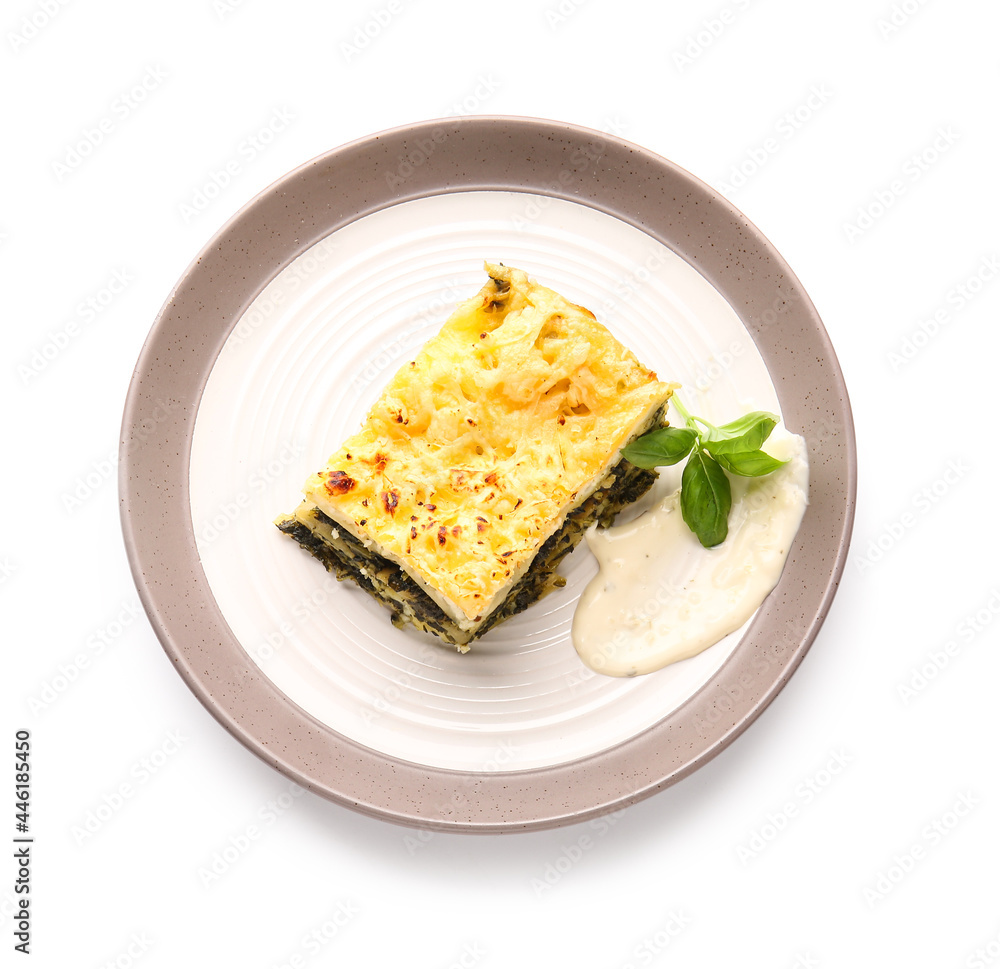 Plate with piece of tasty green lasagna and sauce on white background