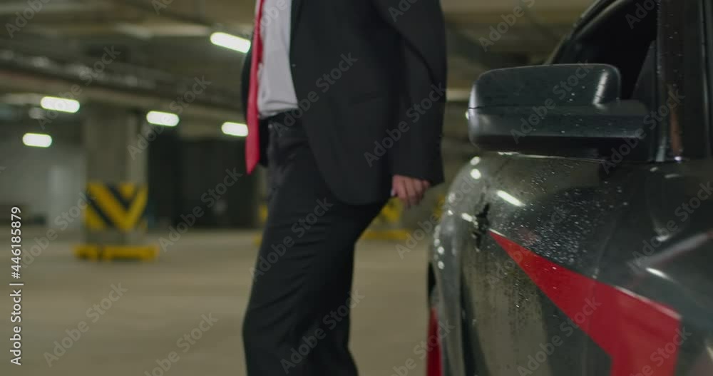 beautiful blonde in a black suit, white shirt and red tie gets out of her black car in an underground parking lot, cinematic shot, slow motion. beautiful blonde in a black suit, white shirt and red tie gets out of her black car in an underground parking lot, cinematic shot, slow motion.