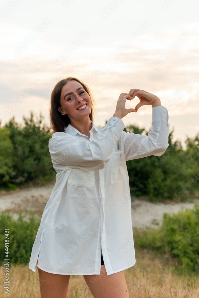 Female making heart shape hand on a garden at sunset. Woman in nature holding heart shape.Love and nature beauty concept Female making heart shape hand on a garden at sunset. Woman in nature holding heart shape.Love and nature beauty concept