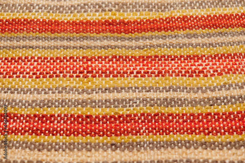 a small handmade rug or mat, woven from red and yellow wool threads, one object close-up