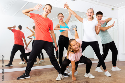 Group portrait of nice teenagers with young female choreographer in modern dance studio