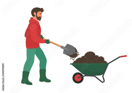 Man pours soil with shovel into wheelbarrow. Farmer working in the garden and digs ground. 