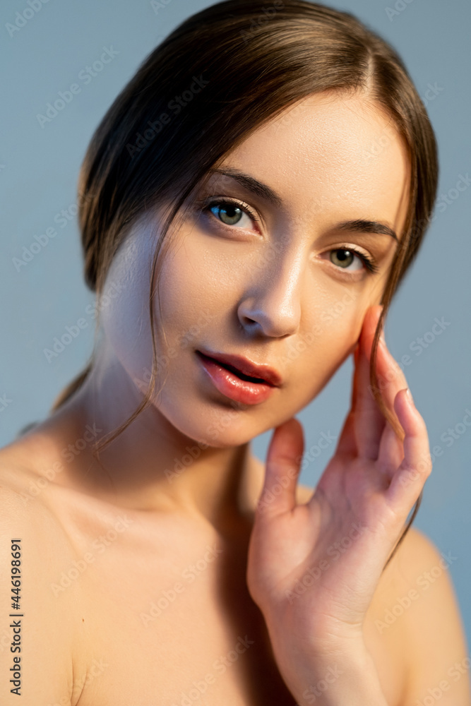 Fototapeta premium Beauty freshness. Female dermatology. Skin health. Facial procedure. Portrait of peaceful young attractive woman with gorgeous radiant face isolated on blue.