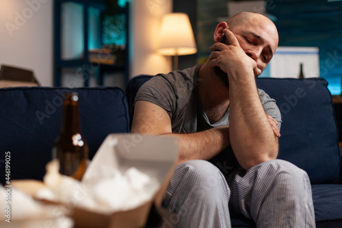 Stressed injured traumatised, frustrated man looking in distance, sitting alone on sofa feeling emotionally unstable, mental desperate, vulnerable suffering from anxiety, chronic disease photo