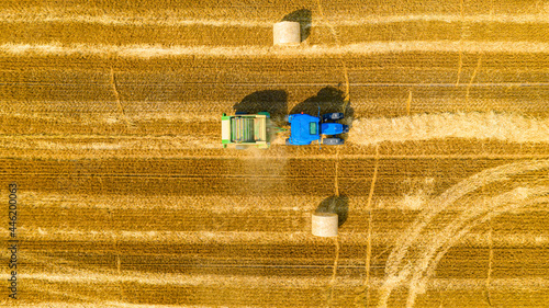 Aerial view of tractor tow trailed bale machine to collect straw from harvested field
