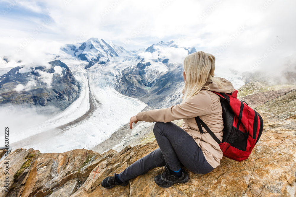 Naklejka premium Rear view of a woman with backpack looking at the view Female hiker relaxing on mountain top.