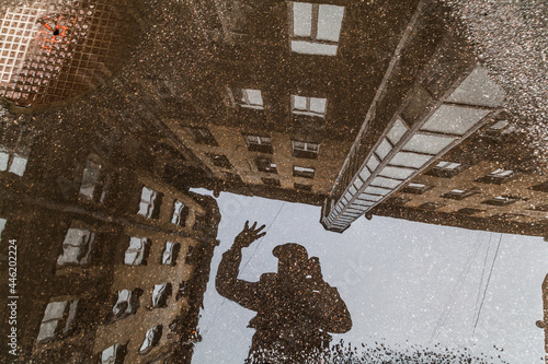 Black silhiuette of man reflected in puddle inside vintage courtyard photo