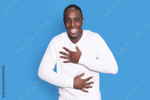 Young handsome man wearing white shirt over isolated blue background smiling with his hands on his chest and grateful gesture on his face.