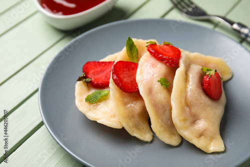 Plate with tasty strawberry dumplings on color wooden background, closeup