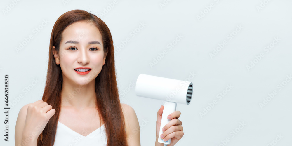 young woman makes hair volume with hairdryer in hand on white background young woman makes hair volume with hairdryer in hand on white background