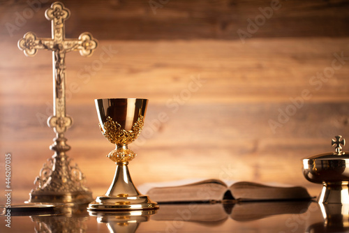 Catholic religion concept. Catholic symbols composition. The Cross, monstrance, Holy Bible and golden chalice on brown background. 