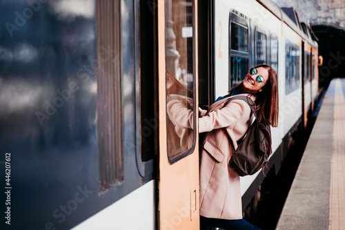 Valokuva smiling young backpacker caucasian woman standing on wagon at train station