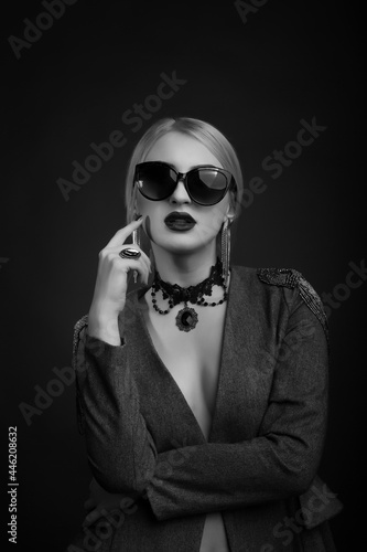 Monochrome studio portrait of a glamor blond woman wears sunglasses and jacket