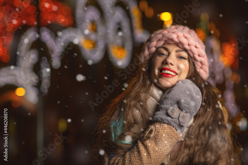 Positive woman walking at the city during snowfall