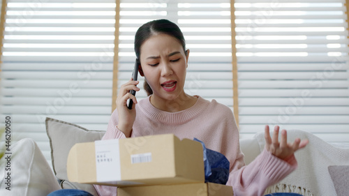 Upset mad asia people young girl consumer sit sofa at home open fake product order, damage post mail buy from online shopping retail store. Shock sad teen woman unbox from wrong bad shipping service.