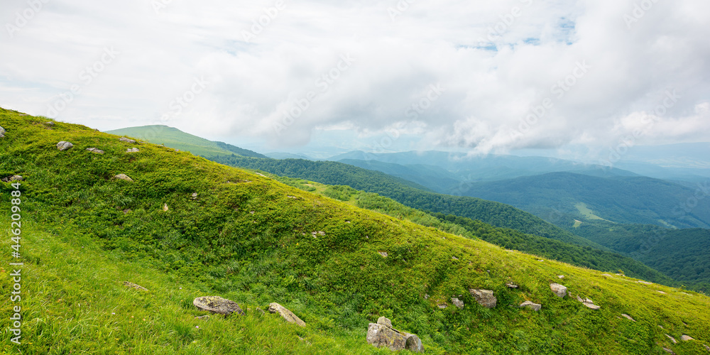 summer mountain landscape. beautiful nature scenery. stones on the grassy hills rolling in to the distant ridge beneath a cloudy sky. travel back country concept