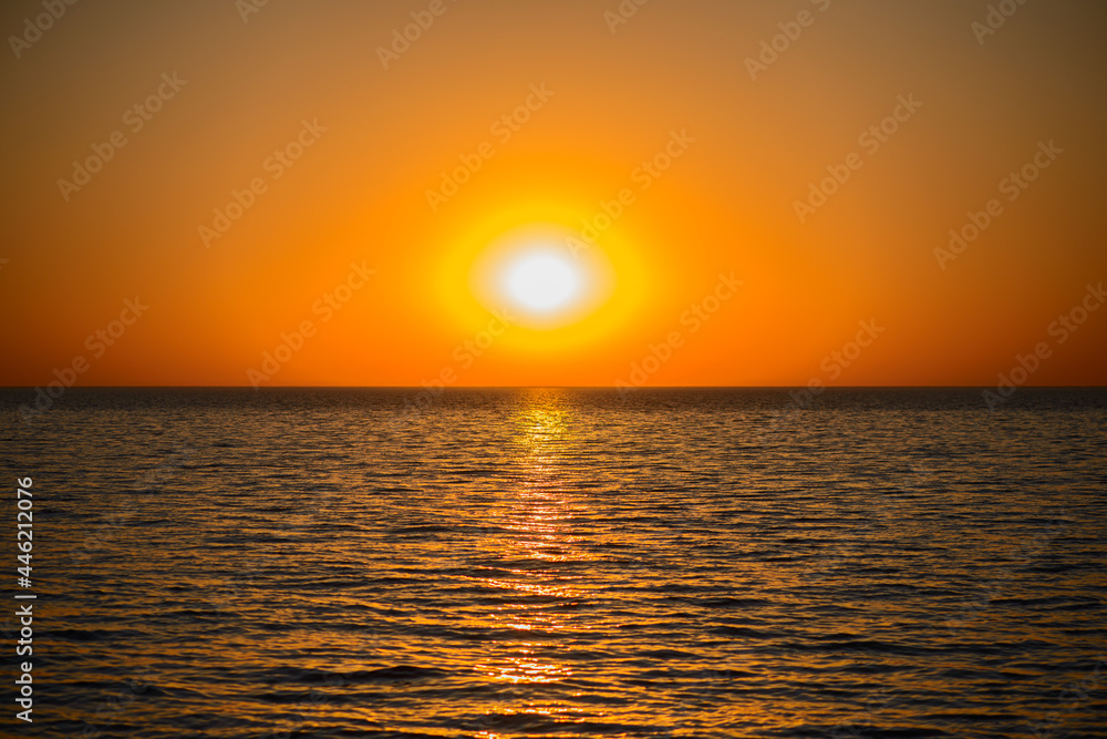 A bright orange sunset over a calm sea