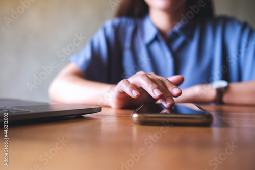 Closeup image of a woman using mobile phone and laptop computer