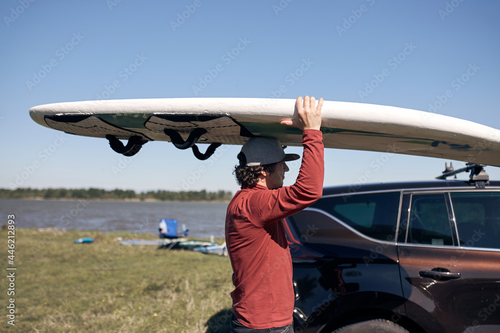 Windsurfer and camper packing and unpacking from a car in nature. Windsurfer and camper packing and unpacking from a car in nature.