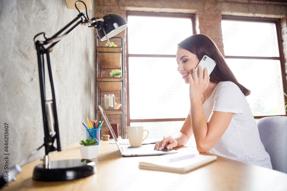 Photo portrait brunette woman sitting at table with laptop talking on cellphone working remotely Photo portrait brunette woman sitting at table with laptop talking on cellphone working remotely