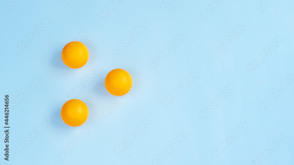 Three ping pong balls on blue background. Image with copy space
