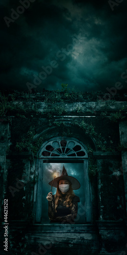Halloween witch wearing medical face mask holding magic wand standing over ancient castle window, full moon with spooky cloudy sky, Halloween and coronavirus or covid-19 concept