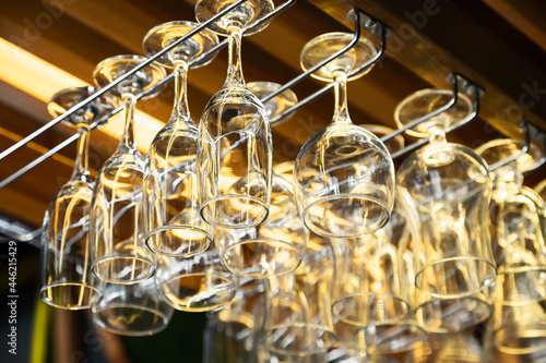 clean wine glasses hang over the bar. Glass, utensils, objects.