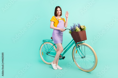 Fototapeta Naklejka Na Ścianę i Meble -  Full body photo of cheerful young happy woman wave hello hold bike smile isolated on teal color background