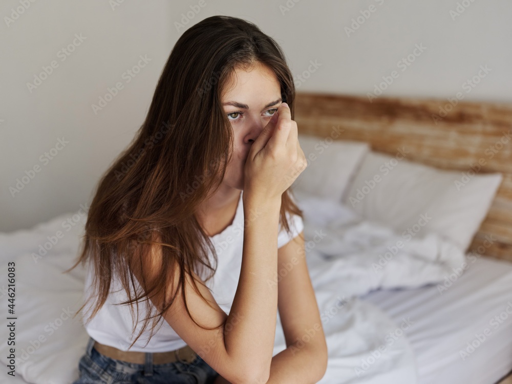 woman sitting on bed thermometer in mouth waiting for result woman sitting on bed thermometer in mouth waiting for result