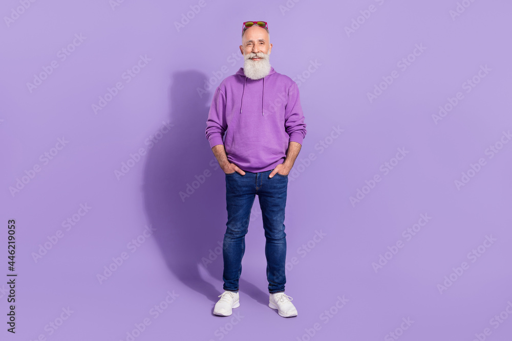 Full length body size view of attractive cheerful grey-haired man hipster holding hands in pockets isolated over purple violet color background Full length body size view of attractive cheerful grey-haired man hipster holding hands in pockets isolated over purple violet color background