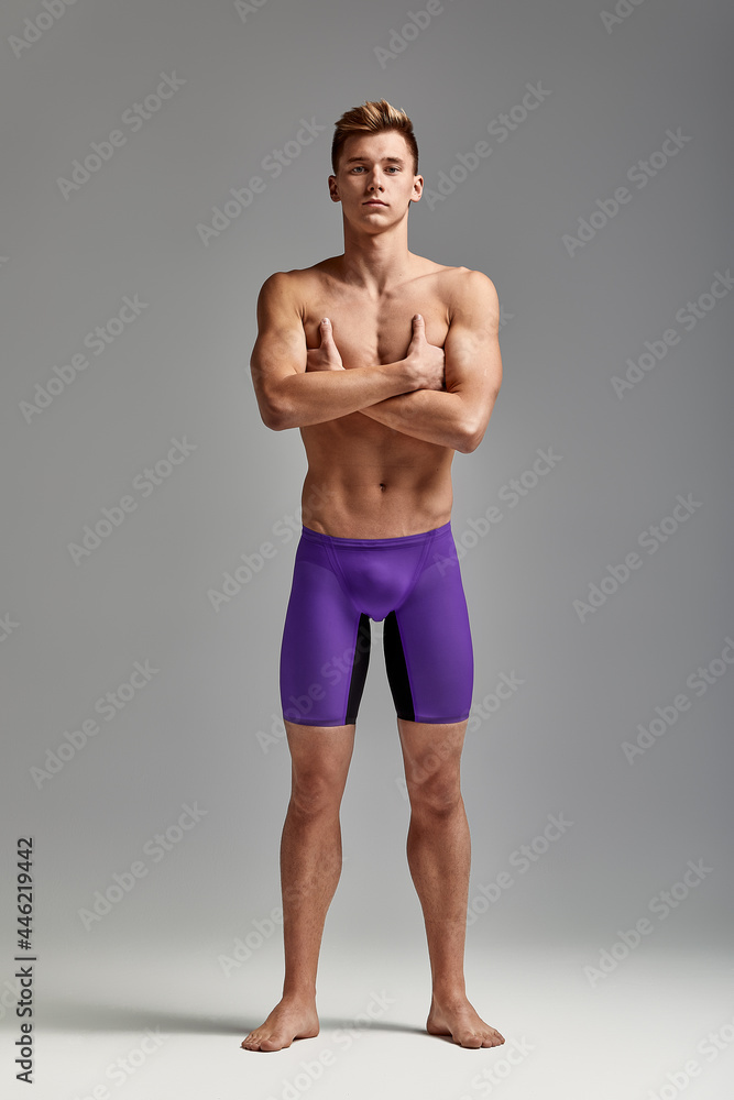 Young swimmer in excellent physical shape in full growth on a gray background with copy space, call for sports, advertising banner Young swimmer in excellent physical shape in full growth on a gray background with copy space, call for sports, advertising banner