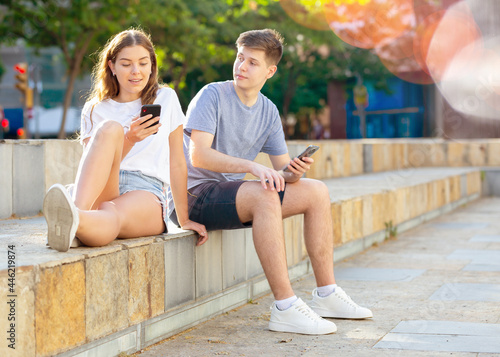 Two teenagers chatting on their smartphone on walking