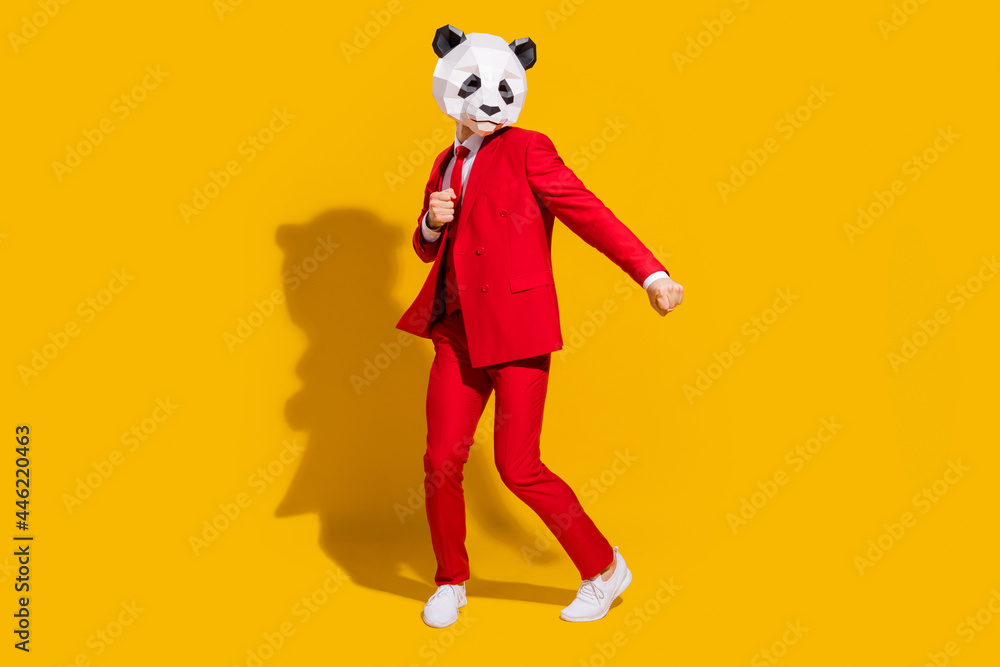 Photo of positive crazy panda guy enjoy dance wear mask red suit tie sneakers isolated on yellow color background Photo of positive crazy panda guy enjoy dance wear mask red suit tie sneakers isolated on yellow color background