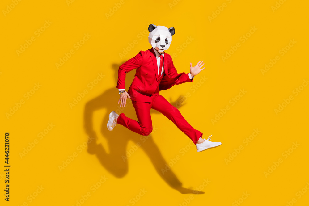 Photo of sporty energetic panda guy jump run wear mask red tux shoes isolated on yellow color background Photo of sporty energetic panda guy jump run wear mask red tux shoes isolated on yellow color background