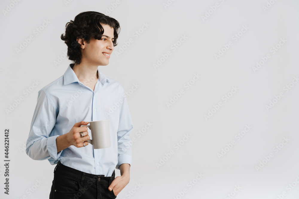 Young brunette man wearing shirt smiling while drinking coffee