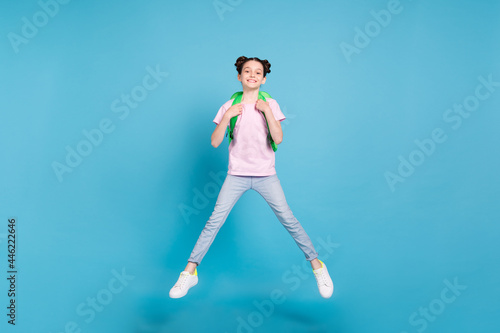 Fototapeta Naklejka Na Ścianę i Meble -  Photo of charming cute schoolgirl dressed pink t-shirt rucksack jumping high smiling isolated blue color background