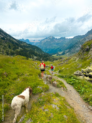 Family of hikers walking through a mountainous natural landscape in Pyrenees.